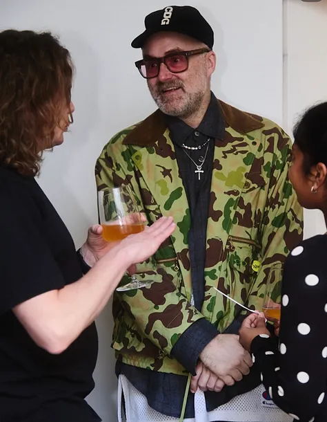 Three people conversing, one wearing a camo jacket and glasses.