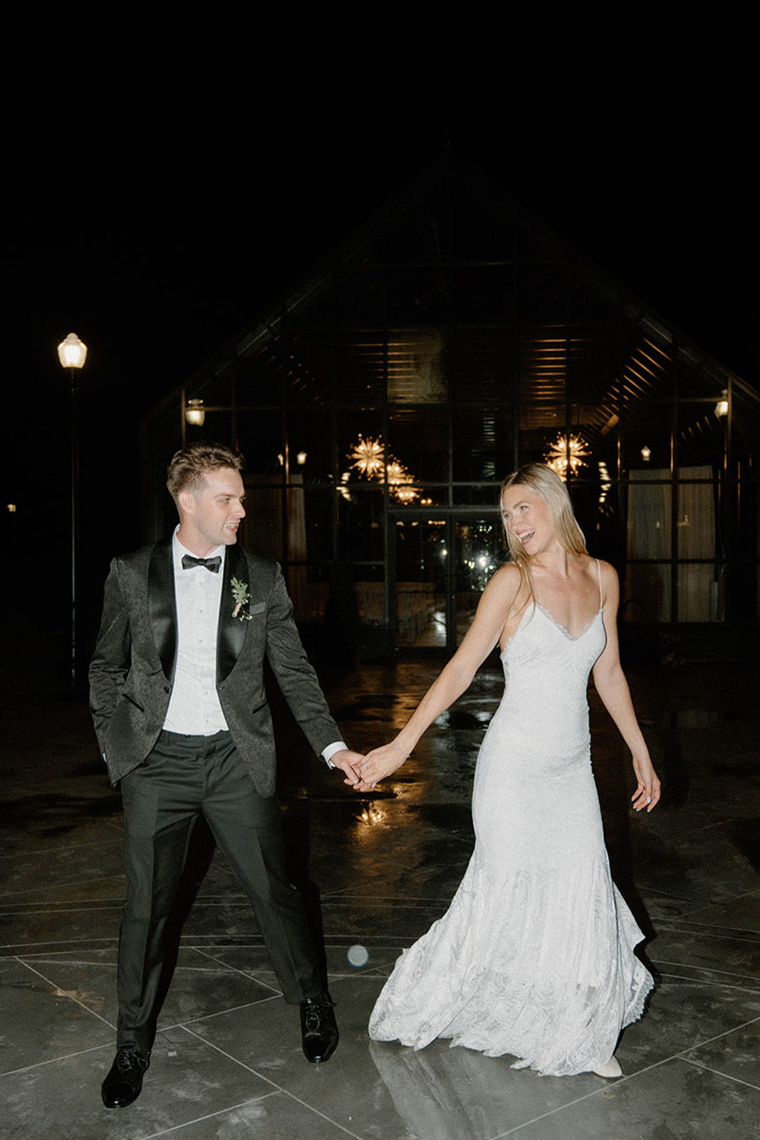 Couple dancing at night, wearing formal attire, holding hands.