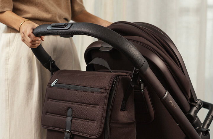 Person holding an iCandy Peach 8 stroller with a matching diaper bag.