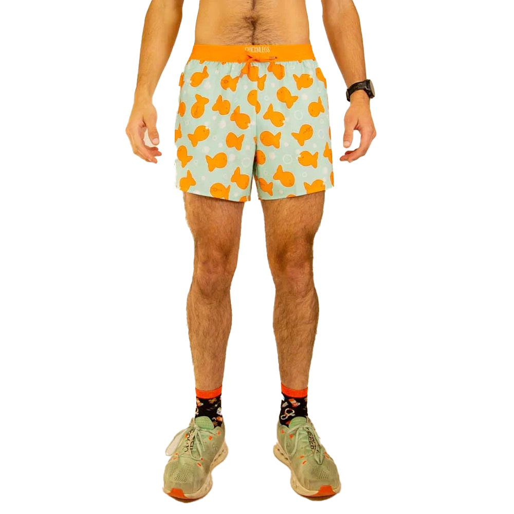 Person wearing patterned shorts and sneakers, standing with hands at sides.