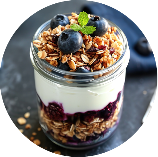 Layered yogurt parfait with Tastefully Simple Blissful Blueberry Jam, granola, and fresh blueberries in a glass jar, garnished with mint.