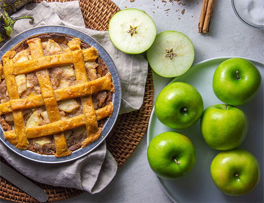 Apple pie with green apples on a table setting.