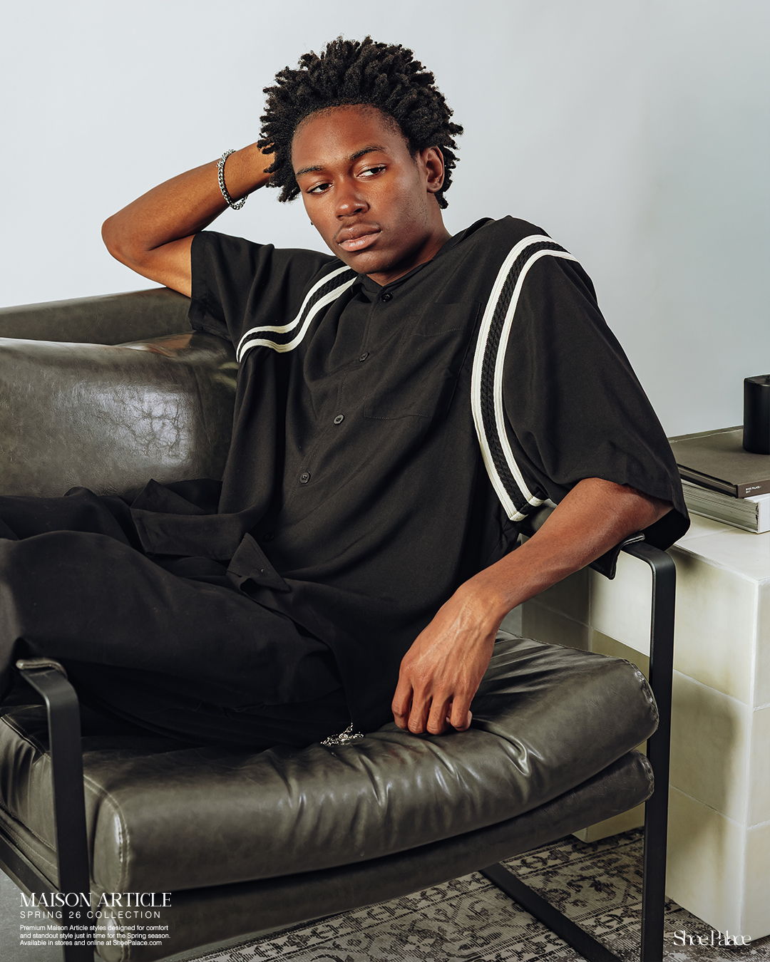 Young person in a black outfit sitting on a chair.