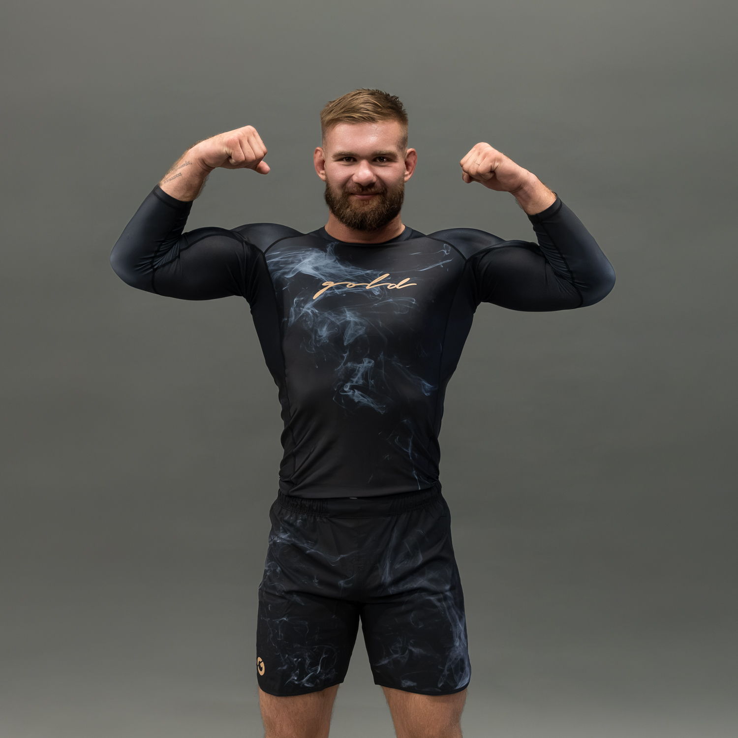 Man flexing muscles in athletic wear against a gray background.