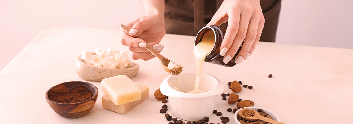 Person pouring a mixture into a bowl surrounded by ingredients on a table.