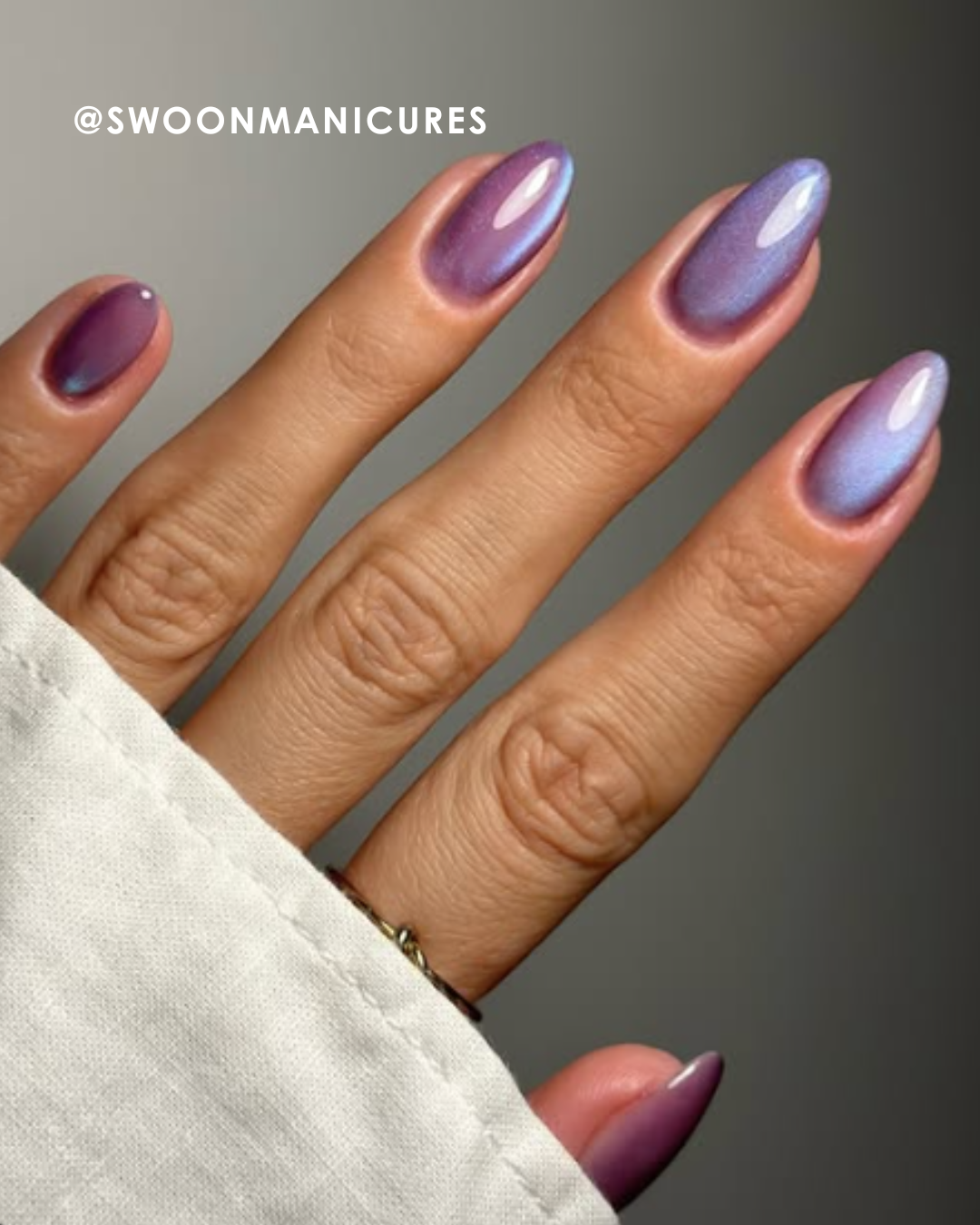 A hand with elegantly manicured, purple gradient nails.