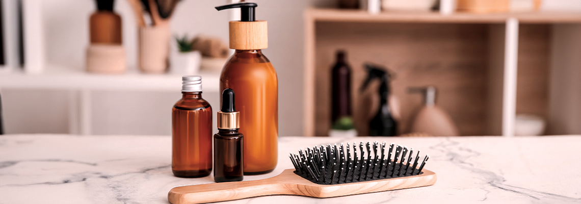 Bottles of hair products and a hairbrush on a marble table.