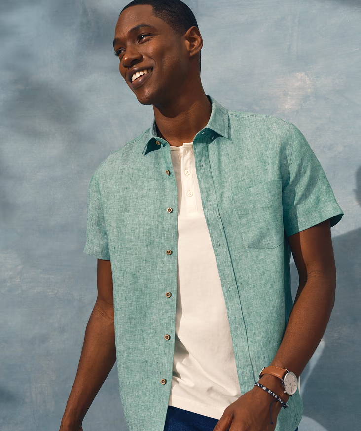 Smiling man in a light green shirt against a blue background.