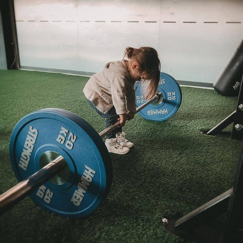Child positioned to deadlift with Hammer Strength bumpers