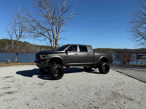 Side profile of lifted gray Ram 2500 Heavy Duty with red suspension and forged wheels parked by lake