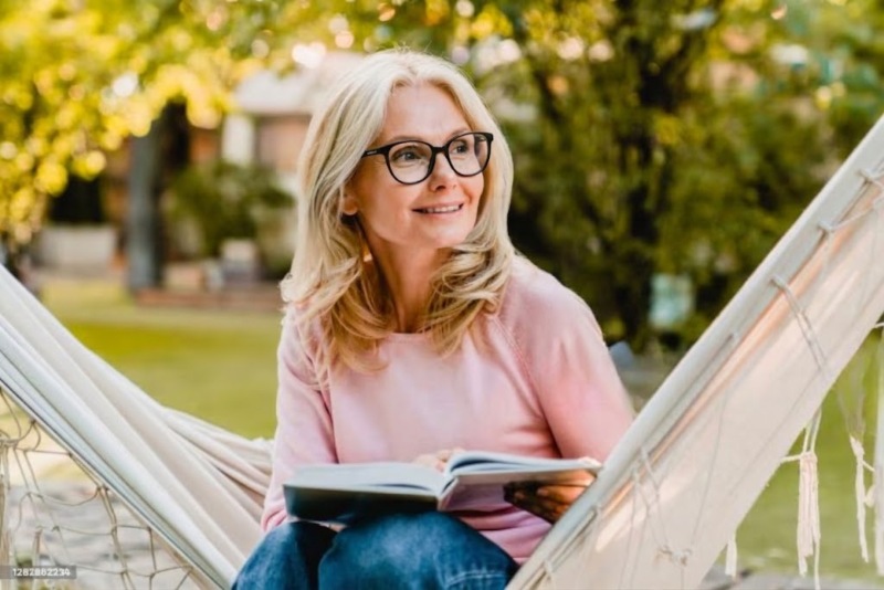 old lady wearing Serene Black reading glasses while enjoying a book outdoors