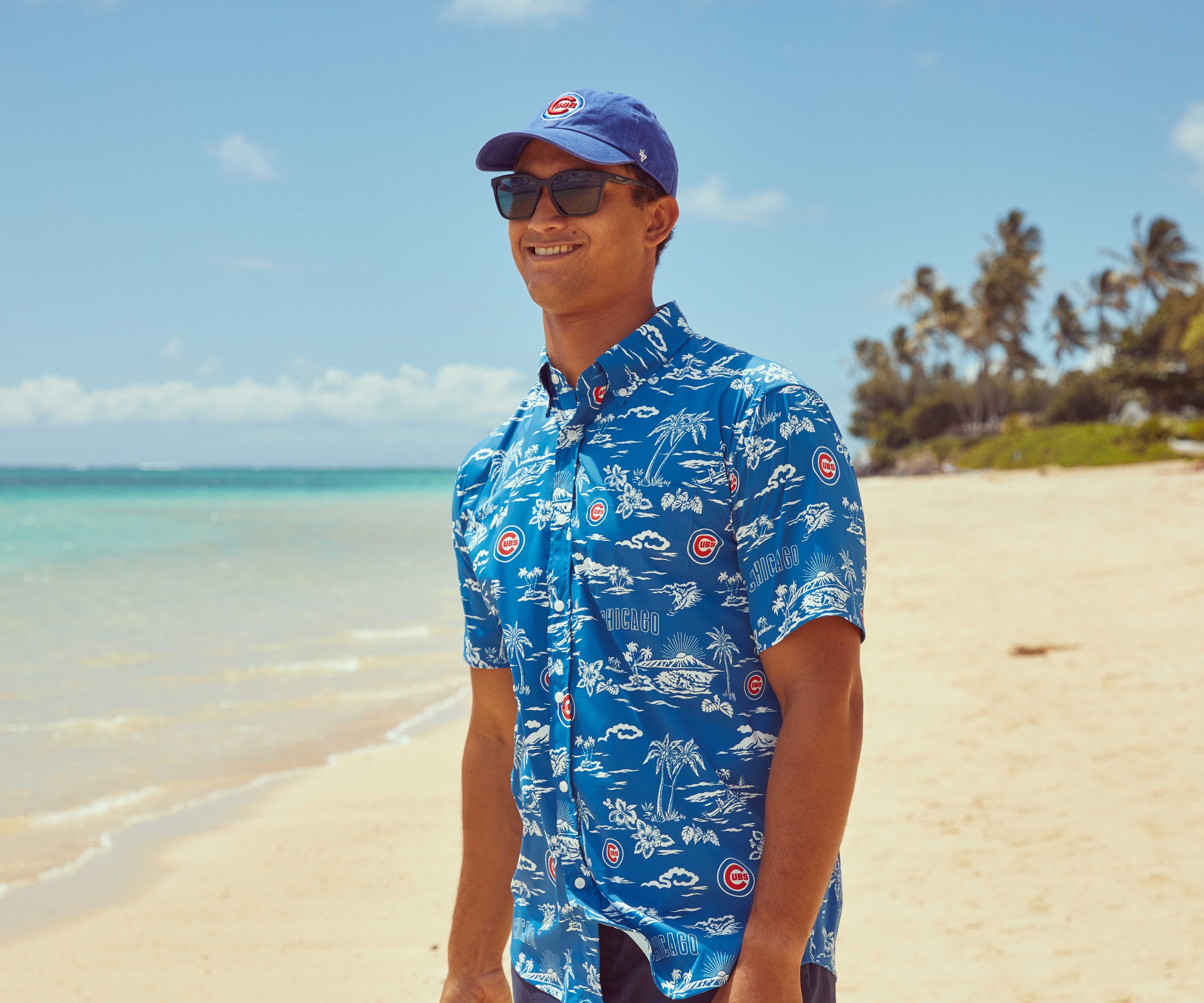 Man in a blue Hawaiian shirt standing on a beach.