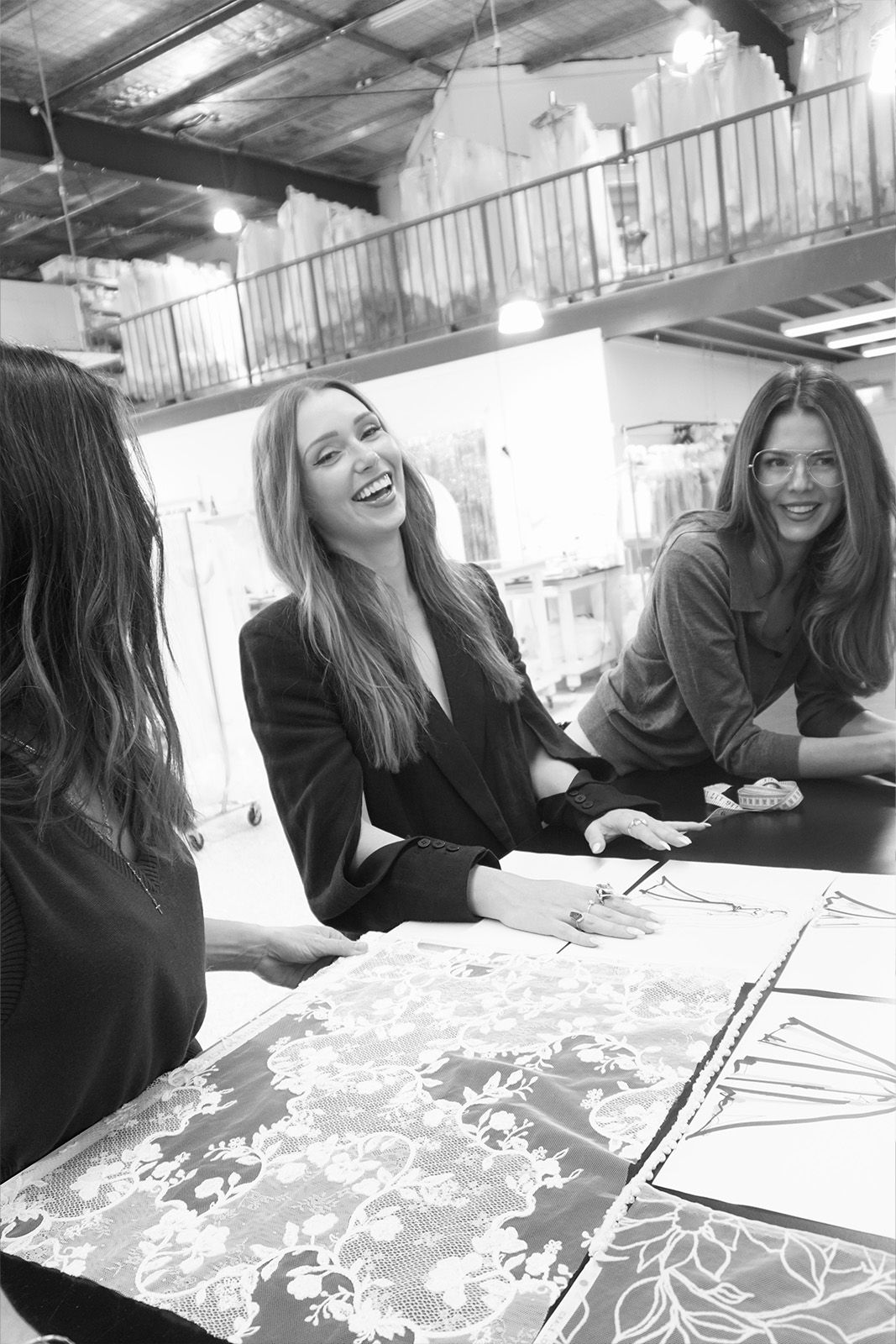Three women smiling and interacting around design materials in a creative space.