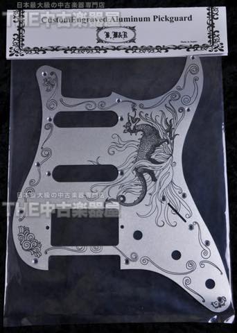 Aluminum guitar pickguard with intricate dragon design, packaged in plastic.
