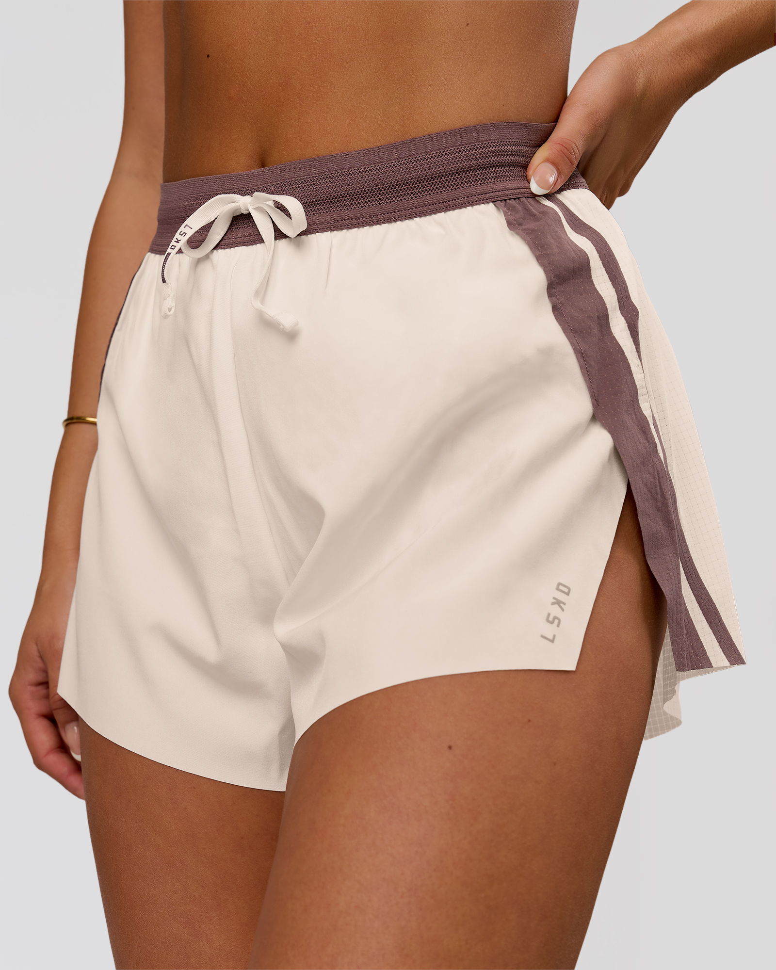 A close-up of a person wearing beige athletic shorts with a purple waistband.